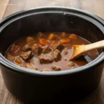 Crock Pot Beef Stew: 2-Ingredient Wonder 5 Spoon lifting Crock Pot Beef Stew from a bowl
