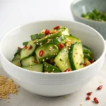 Smashed Cucumber Salad: How To Make It In 6 Steps 9 Finished smashed cucumber salad in a white bowl with sesame and chili
