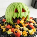 Watermelon monster fruit bowl with colorful Halloween appetizers.
