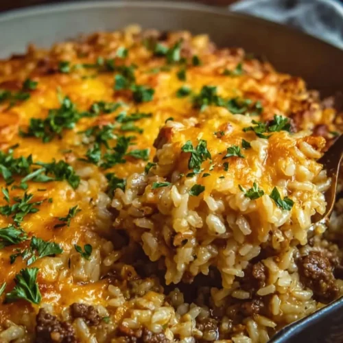 Cheesy ground beef rice casserole served in a baking dish with melting cheese on top