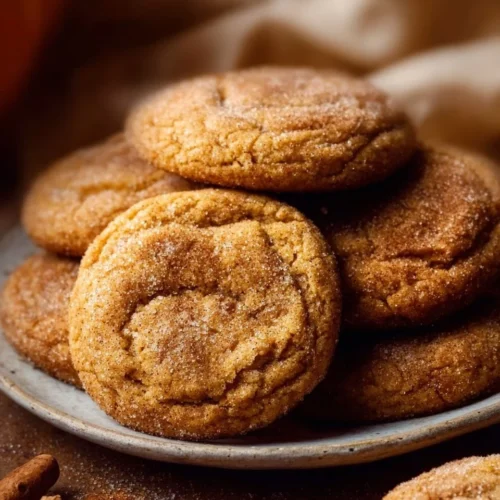 Chewy Pumpkin Snickerdoodle Cookies on a plate with a sprinkle of cinnamon sugar