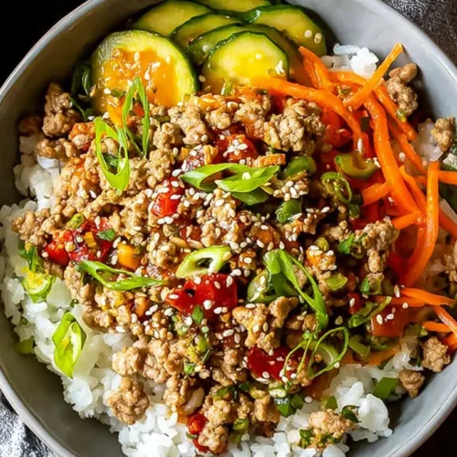 A healthy ground turkey meal in a bowl with colorful vegetables and rice.