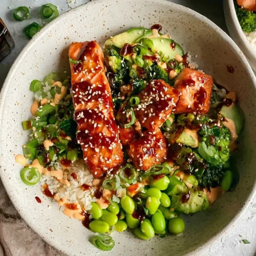 A vibrant bowl of Honey Sriracha Glazed Salmon Bowls with rice and fresh vegetables.