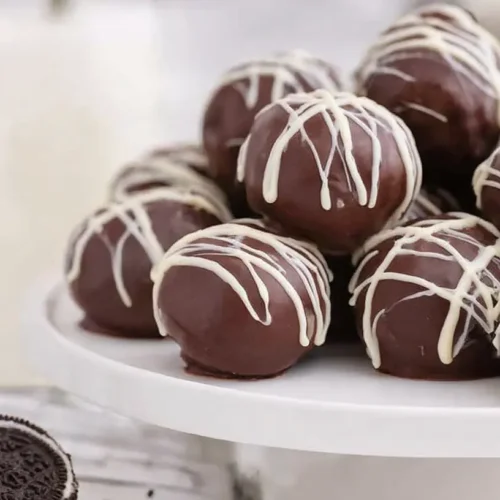 Oreo Cream Cheese Balls: 1 Perfect Treat 2 A white plate filled with perfectly round Oreo cream cheese balls.