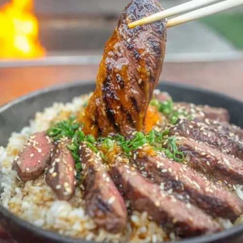 A vibrant grilled steak bowl with sliced steak, rice, and vegetables.