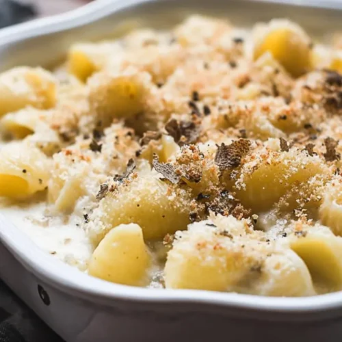 A serving of rich, creamy truffle mac and cheese garnished with fresh herbs.