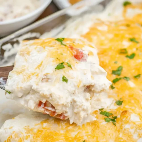 Creamy White Chicken Enchiladas: How I Make 1 Dish 2 A baking dish filled with creamy white chicken enchiladas, topped with melted cheese and fresh cilantro.