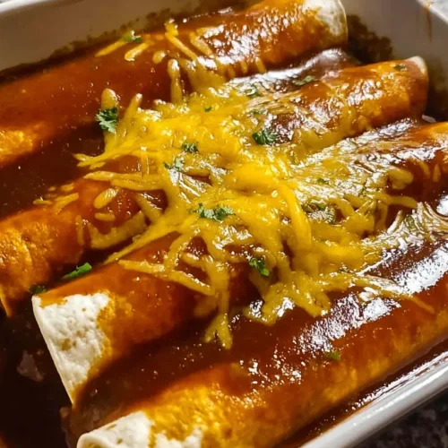 A plate of ground beef enchiladas topped with red sauce and melted cheese.