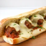 A close-up of a hot cheesy meatball sub, fresh out of the oven
