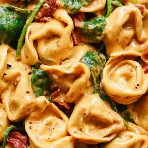 A close-up of creamy Marry Me Tortellini in a bowl, garnished with fresh herbs.