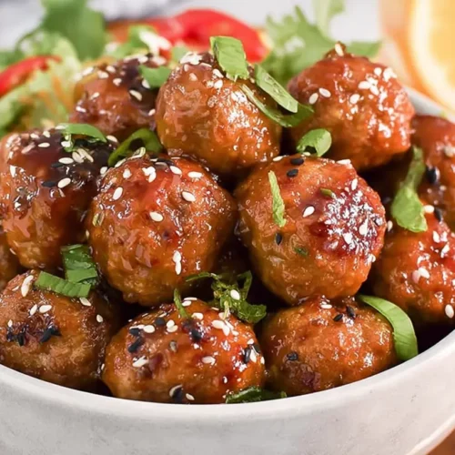 Slow Cooker Honey Garlic Meatballs: The 1 Best Recipe 2 A close-up of slow cooker honey garlic meatballs in a glazed sauce, garnished with sesame seeds and green onions.