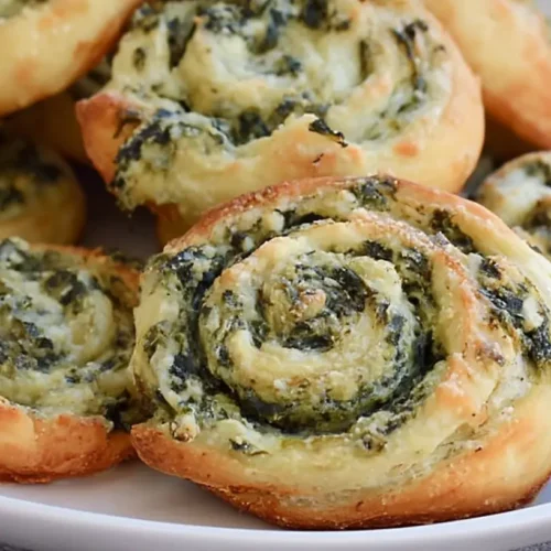 A platter of golden-baked spinach dip in bite-sized pinwheels, ready to serve.