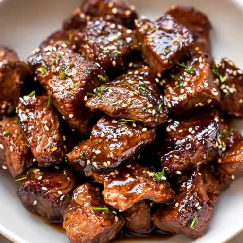 A close-up of sweet and sticky steak bites drizzled with glaze.