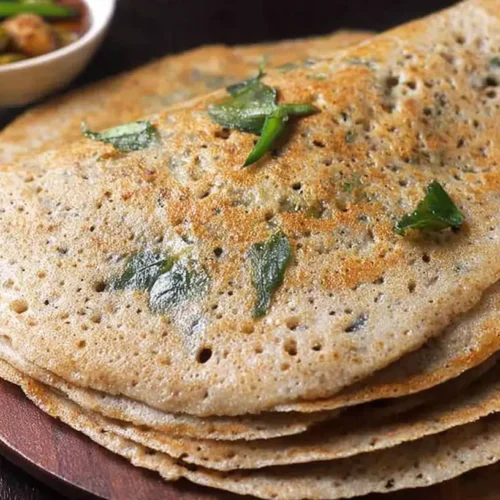 WHEAT DOSA | GODHUMA DOSA: Your 1 Go-To Guide 2 A freshly made wheat dosa, golden brown and perfectly cooked, on a white plate.