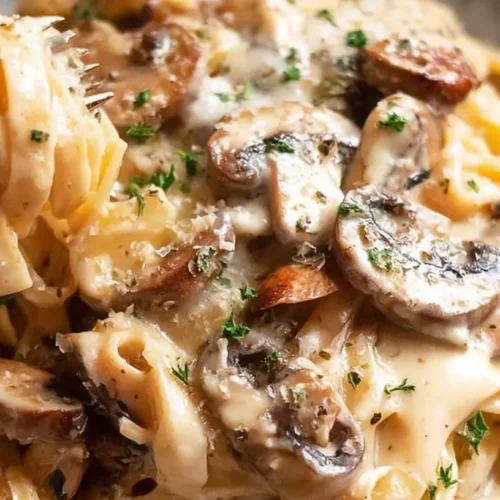 A bowl of creamy mushroom pasta dinner, garnished with fresh herbs