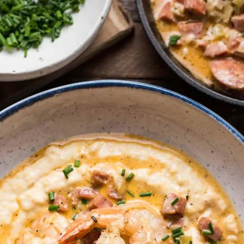 A plate of shrimp and grits garnished with fresh herbs