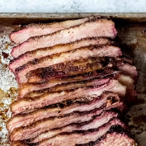 A perfectly cooked Texas smoked brisket with a deep bark and juicy interior, sliced on a cutting board.